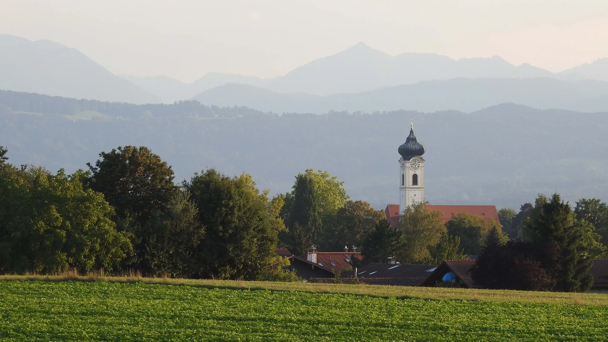 Bad Aibling seen from the north, with a church tower and the Mangfall mountains in the distance.